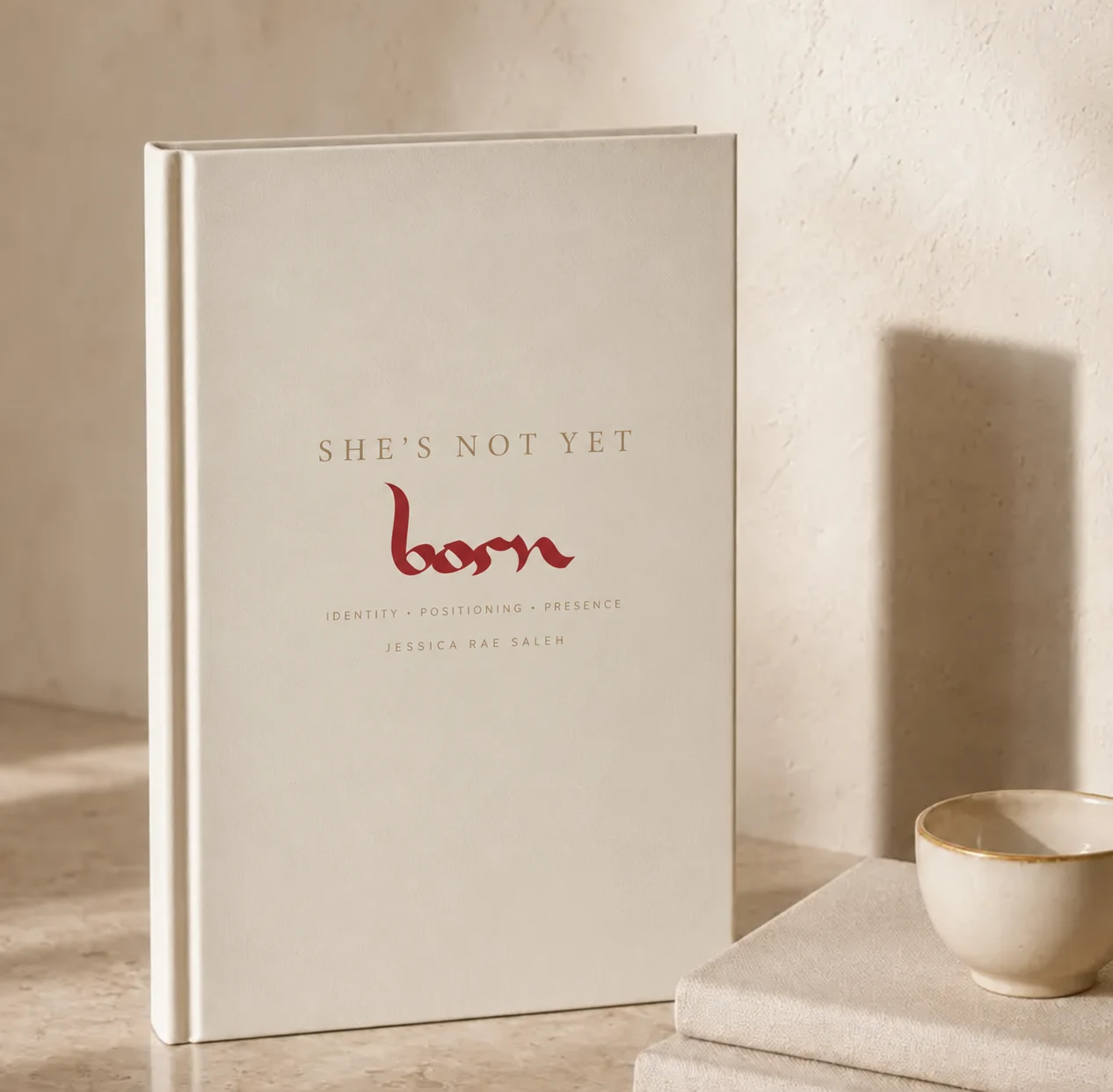 She's Not Yet Born book on a marble surface beside a cup